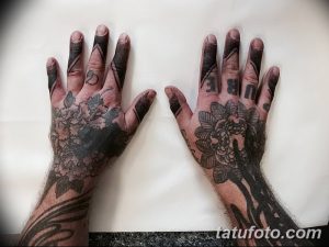 Фото тату: руки полностью покрыты черными татуировками с геометрическими узорами и цветочными мотивами. Детализированный рисунок на предплечьях и пальцах.