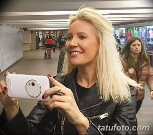 Фото тату: надпись "Love" на пальце девушки, держащей телефон. Модный и современный образ.