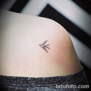 Фото тату: маленькая черная татуировка птички на плече. Минималистичный рисунок татуировки с тонкими линиями.