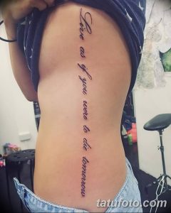 Длинная надпись тату "Live as if you were to die tomorrow" на боку, выполненная изящным шрифтом черного цвета.