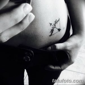 Фото тату: небольшая татуировка с изображением стрелы, пронзающей перо, выполненная в черном цвете на ключице в минималистичном стиле.