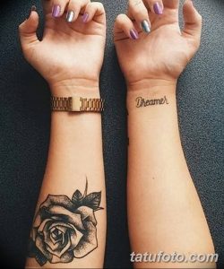 Фото тату розы на одном запястье и надписи 'Dreamer' на другом. Черно-белый дизайн, символизирующий красоту и мечты.