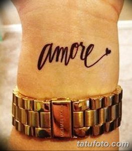Фото тату надписи 'Amore' на запястье. Черный контур, небольшое сердечко, минималистичный дизайн. Идеально для любителей простых и романтичных татуировок.