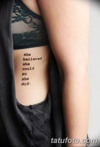 Фото минималистичной татуировки на ребрах: черная надпись "she believed she could so she did". Изящный рисунок татуировки.