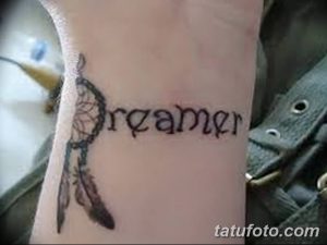 Фото тату ловца снов и надписи 'Dreamer' на запястье. Черно-белый рисунок в тонком стиле. Символизирует защиту от кошмаров и веру в мечты.