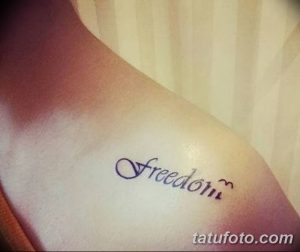 Фотографія тату з написом "Freedom" виконаним красивим шрифтом та прикрашеним маленьким сердечком, розташованим на ключиці.