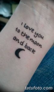 Фото тату с надписью "I love you to the moon and back" и изображением полумесяца на запястье. Черно-белый рисунок татуировки, выполненный каллиграфическим шрифтом.