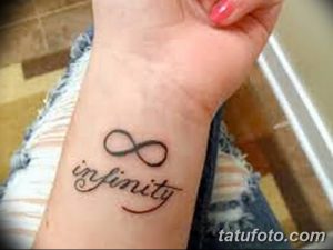Фото тату: черная татуировка символа бесконечности с надписью "infinity" на запястье. Минималистичный дизайн, символизм вечности и любви.