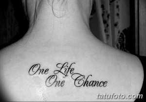 Фото тату: надпись "One Life One Chance" на спине человека. Черный шрифт, каллиграфия.