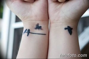 Фото парных тату на запястьях с изображением силуэтов птиц, сидящих на ветке, выполненных в черном цвете.
