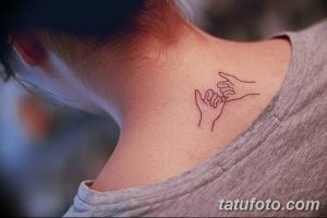 Фотография нежной татуировки на затылке, изображающей две руки, соединенные мизинцами. Тонкие линии и пастельные тона создают романтичное настроение.