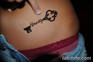 Фото тату ключа с надписью 'Honesty' на женском теле. Черно-белый рисунок татуировки, выполненный в минималистичном стиле, расположен на боку.
