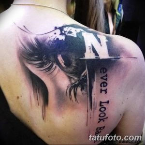 Фото тату портрета девушки с буквой 'N' и надписью 'Never Look Back' на спине. Детализированный рисунок татуировки в черно-серых тонах.