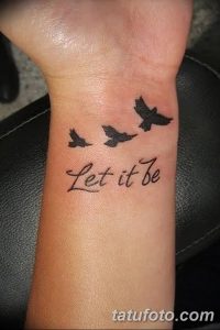 Фото тату на запястье с изображением трех летящих птиц и фразы 'Let it be'. Черно-белый рисунок татуировки, символизирующий свободу и принятие.