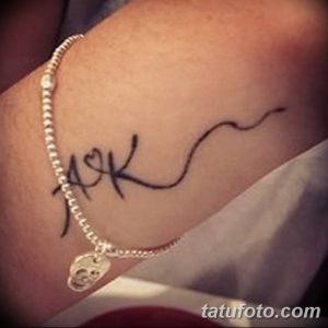 Фото тату: черные инициалы 'A' и 'K', соединенные сердечком, на запястье. Изящный рисунок татуировки для пар.