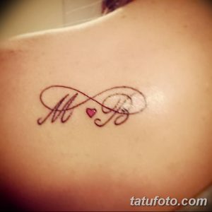 Фото тату на лопатке: красивые инициалы 'M' и 'B', переплетенные с сердцем и символом бесконечности. Романтичный и нежный рисунок.