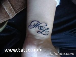Фото тату: черные инициалы 'M' и 'L', выполненные каллиграфическим шрифтом, на запястье.