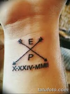 Фото тату: две перекрещенные стрелы с инициалами 'E' и 'P' и римскими цифрами 'X-XXIV-MMII' на запястье.