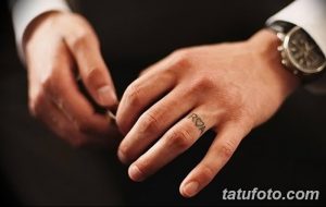 Фото парных тату на пальцах: инициалы 'R' и 'A' с сердечком между ними, выполненные в черном цвете, минималистичный дизайн.