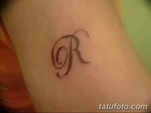 Фото тату: маленькая буква 'R' на запястье. Черно-белый рисунок татуировки, простой дизайн.