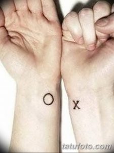 Фото тату: минималистичные татуировки 'O' и 'X' на запястьях двух людей. Простые черные символы, парные татуировки.