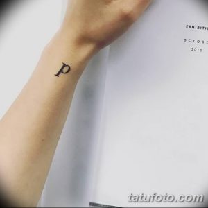 Фото тату: маленькая черная буква 'p' на запястье. Минималистичный дизайн, простой рисунок татуировки для девушек.