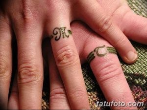 Фото парных тату инициалов 'M' и 'C' на пальцах рук. Рисунки татуировок выполнены в растительном стиле с использованием зеленых и коричневых оттенков.