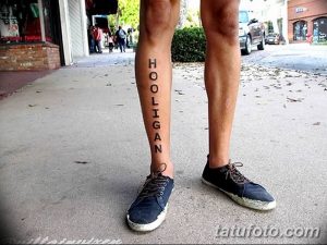Фото тату на ноге: вертикальная надпись 'HOOLIGAN', выполненная простым черным шрифтом, создающая дерзкий и бунтарский образ.