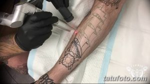 Фото тату: мастер наносит контур татуировки на руку клиента. Виден эскиз с изображением корабля и морских элементов.