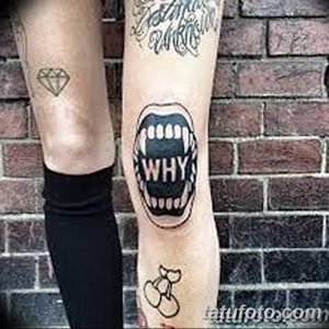 Фото тату открытых губ с зубами и надписью 'WHY' на ноге. Черно-белый рисунок с ярким выражением и необычным дизайном.