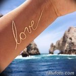 Фото татуировки хной на руке: надпись "love" золотого цвета, выполненная каллиграфическим шрифтом. Романтичный и минималистичный дизайн.