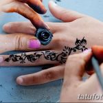 Фото тату: процесс нанесения мехенди на руку, мастер аккуратно наносит хну с помощью специального инструмента.