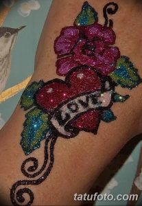 Фото тату с использованием блесток, изображающее розовую розу и надпись LOVE. Яркий и привлекательный рисунок для тех, кто любит выражать свои чувства.