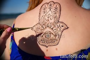 Фото тату хной на спине, изображение 'Руки Фатимы' (Хамасы) с детальным узором и голубым камнем в центре.