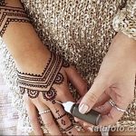 Фото процесса нанесения татуировки хной на руку, мастер наносит узор с помощью конуса, видны детали рисунка.