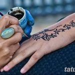 Фото тату мехенди: мастер наносит узоры хной на руку девушки, демонстрируя процесс создания временной татуировки.
