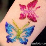 Фото тату: две яркие бабочки, выполненные блестками на коже. Разноцветные крылья создают праздничное настроение. Временное украшение тела.