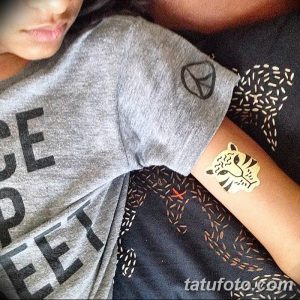 Фото тату: золотая татуировка в виде головы тигра на руке. Небольшой, стильный рисунок татуировки для вдохновения.