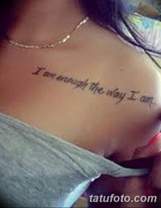 Фото тату: фраза 'I am enough the way I am' нанесена на ключицу девушки, выполненная изящным шрифтом в черных тонах.