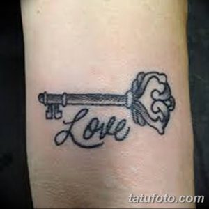 Фото тату: старинный ключ с надписью 'Love', выполненный в черном цвете на запястье. Детализированный рисунок татуировки.