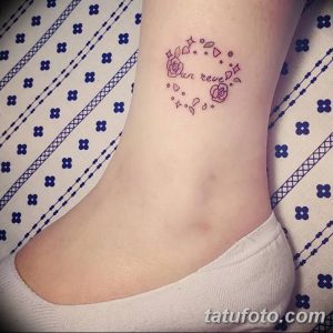 Фото тату с надписью "Sun reve" и небольшими розами на животе. Минималистичный дизайн в нежных розовых тонах.