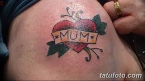 Фото татуировки в стиле олдскул: красное сердце с надписью "Mum" на ленте. Традиционный рисунок, простой дизайн, небольшая татуировка.