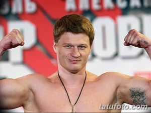 Фото тату на предплечье Александра Поветкина, небольшая надпись черным цветом, выполненная в минималистичном стиле. Изображение демонстрирует спортивную форму и татуировку.
