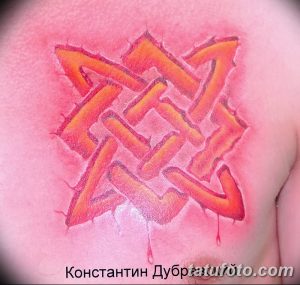 Фото тату кельтского узла на груди, выполненного в ярком оранжевом цвете с эффектом капель. Оригинальный и привлекательный дизайн для мужчин.