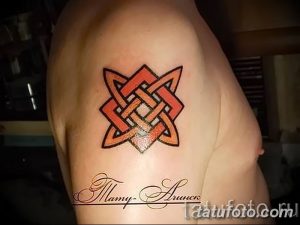 Фото татуировки кельтского узла на плече мужчины. Рисунок выполнен в красно-черной гамме, с четкими контурами и геометрическим орнаментом.