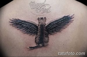 Фото тату: черная кошка с большими крыльями, расположенная на спине. Детализированный рисунок, реалистичные перья, эффект полета.