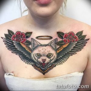 Фото тату кота с нимбом, розами и крыльями на груди. Традиционный стиль татуировки с яркими цветами и четкими контурами.