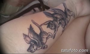 Фото тату нескольких серых кошек с крыльями, парящих в воздухе на руке. Детализированный рисунок в реалистичном стиле.