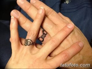 Фото парных тату на пальцах, изображающих переплетенные символы. Черно-белый рисунок татуировки, символизирующий связь и единство.