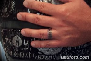 Фото татуировки на пальце мужчины, выполненной в виде кельтского узла. Черно-серый рисунок с детализированной текстурой.